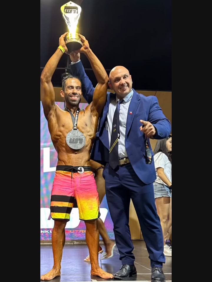 Atleta campeón en escenario con trofeo y preparador